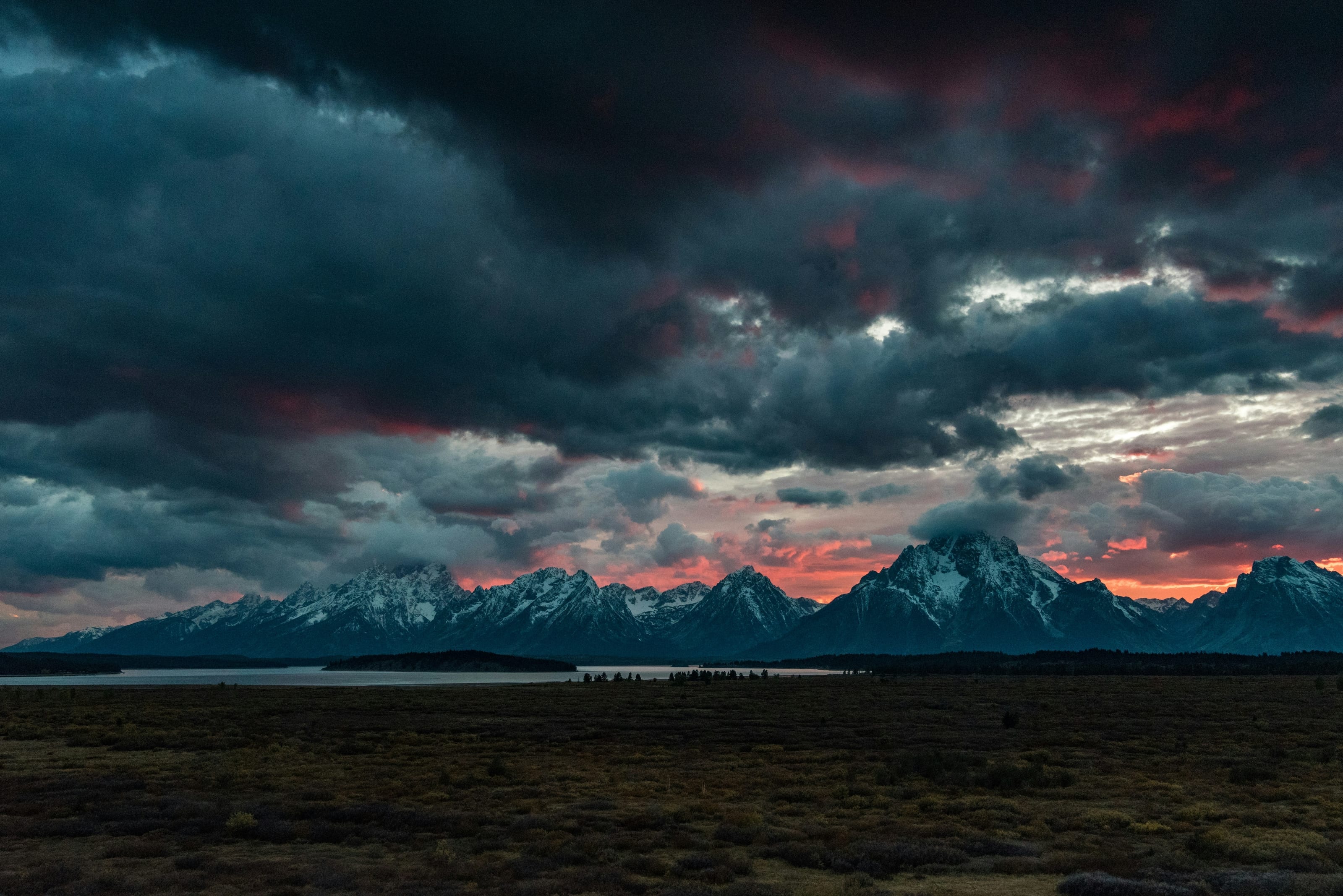 Snow-capped mountain range under storm clouds at last light